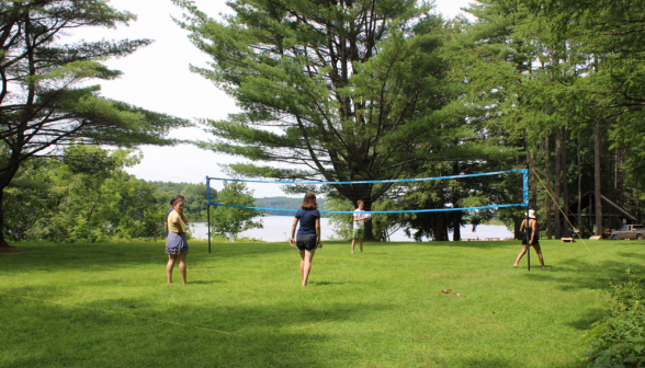 A game of volleyball takes place in a nearby field with a view of the water