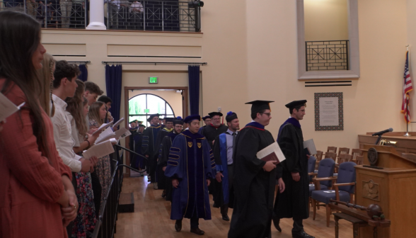 The faculty files into the auditorium
