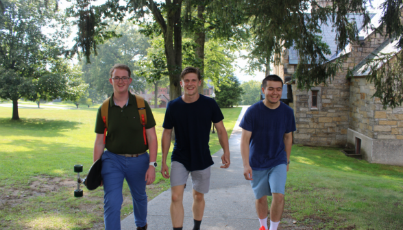 Three students walk toward Gould, passing the chapel