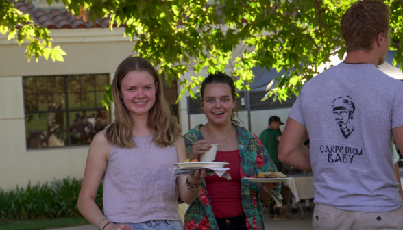 Students with food in hand select a spot at the tables