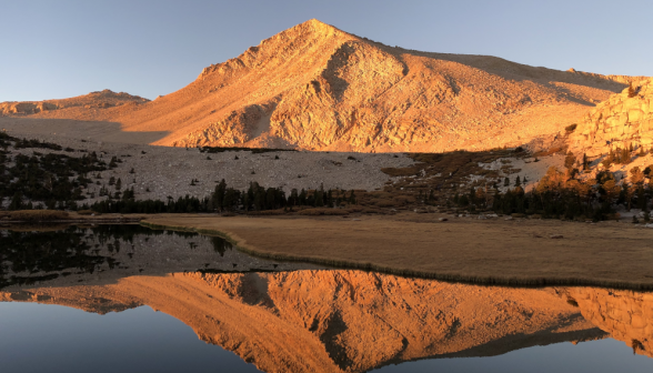 A golden-red mountain in the sunset, perfectly reflected in a lake at its foot