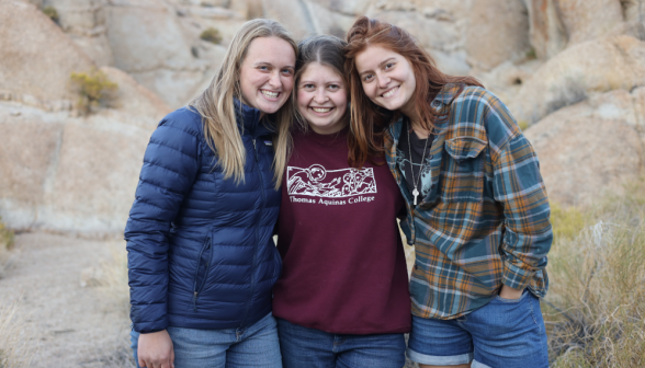 Three pose for a picture afront a large rock outcropping