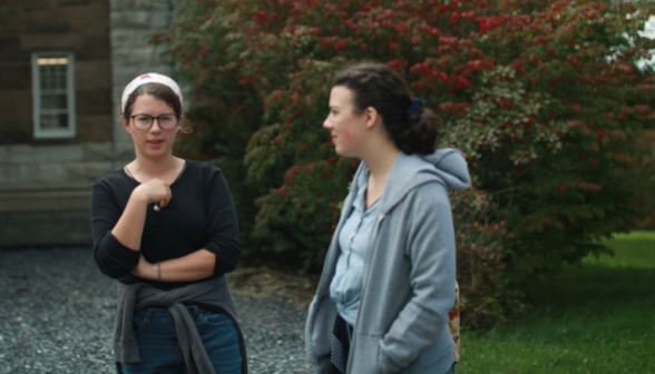 Two students converse outside one of the buildings