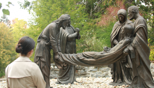 A student contemplates a statue of the faithful laying Christ in the burial chamber