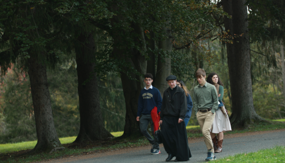 A group of students walk down the road with Fr. Markey