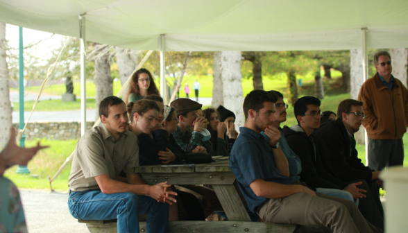 Assembled on picnic benches, the students listen to a talk