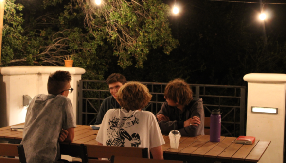 Students chat at one of the outdoor tables