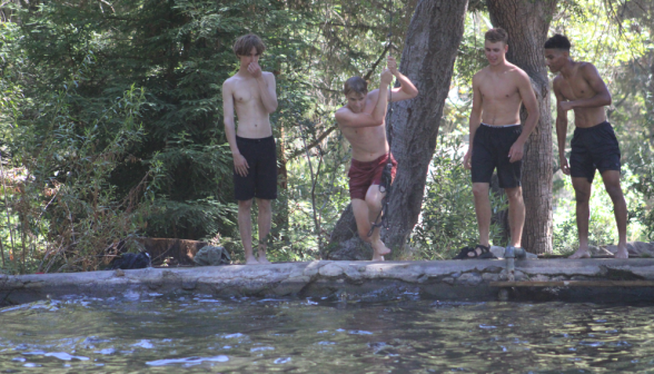 One student takes the rope swing while his companions look on from the side