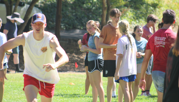 Students congregate on one side; in the foreground, another student runs full tilt toward the camera