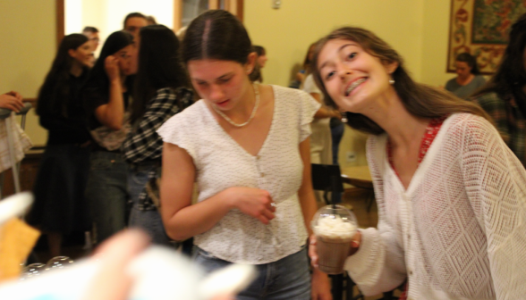 Student smiles for the camera as another examines the drink choices