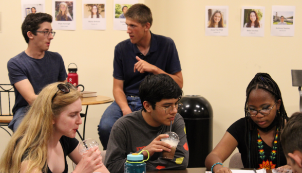 Three students in the foreground study while two in the background discuss