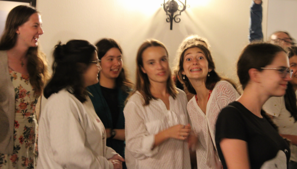 Amid a crowd of girls in the women's dorm, two students smile at the camera