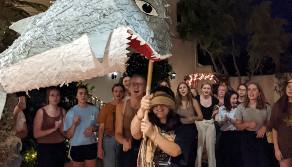 A blindfolded student takes a swing at the piñata