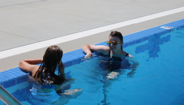 Two students relax and chat in the pool