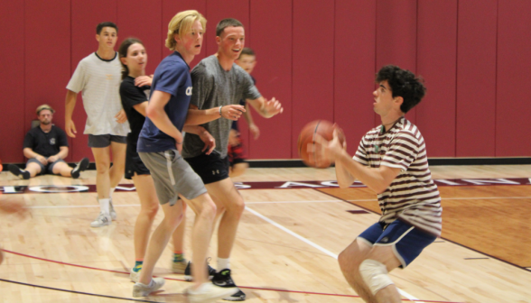 Mid-action: in the basketball game, a student takes a shot