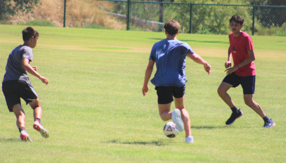 Three students playing soccer