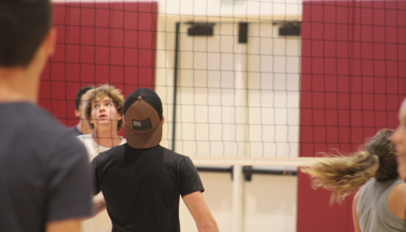 Close-up: tense players at the volleyball net watch to see which side the ball will come down on