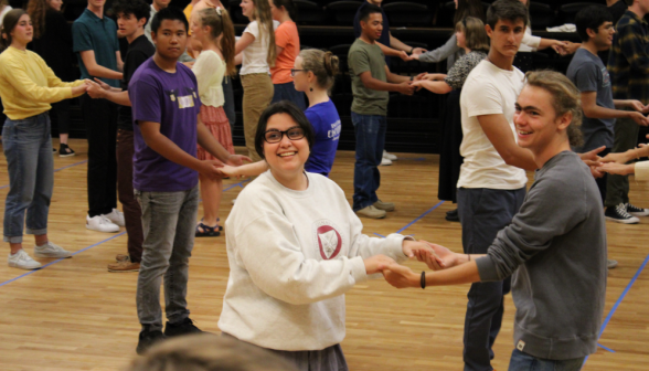 Across the floor, student pairs take up the swing position