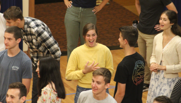 Students laugh and chat to one side of the floor