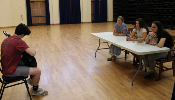 A student with a guitar auditions for Open Mic Night