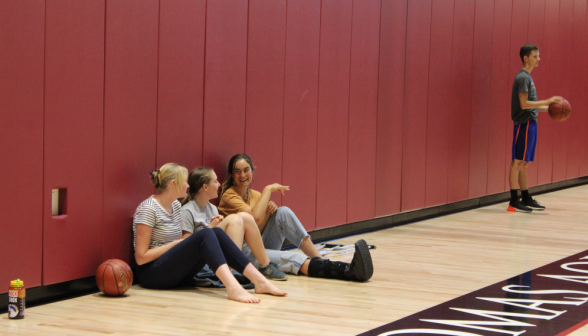 Three sit and chat on one side of the gym