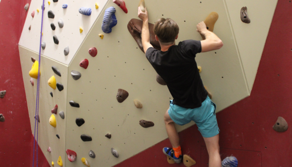 A student free climbs the rock wall