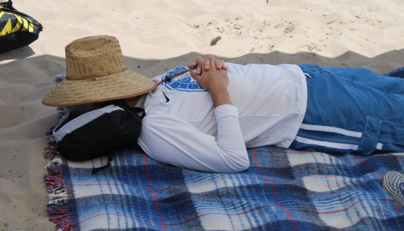 Hat over face, a student naps on a towel