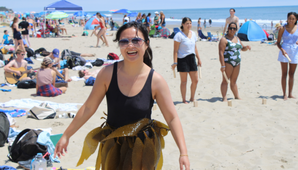 A student on the beach wearing a pretend skirt of seaweed