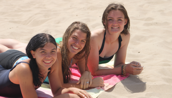 Three tanning on beach towels