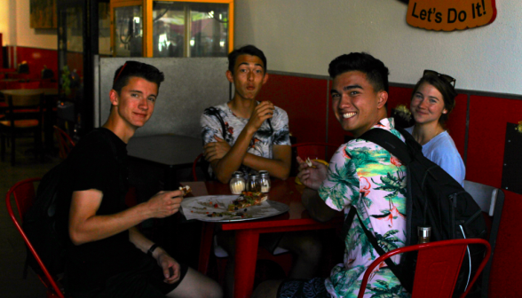 Three programmers and a prefect pose at an indoor table with pizza