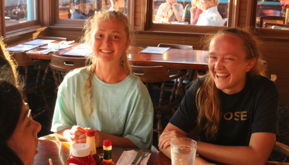 Two smile for a camera at one end of a restaurant table