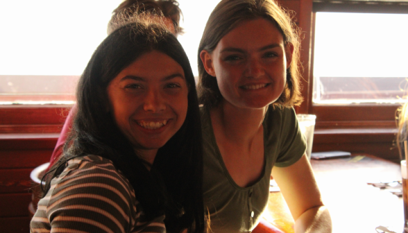 Two students smile for a camera at a restaurant table