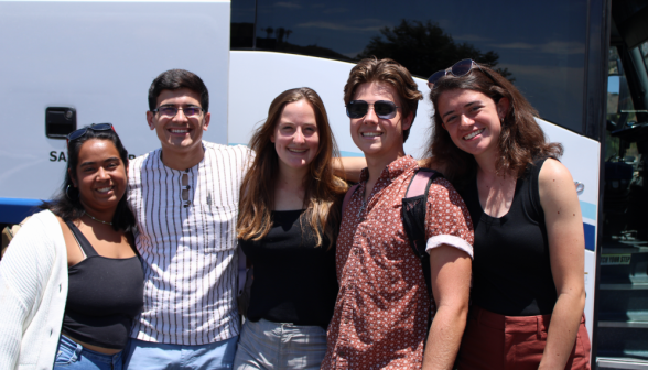 Three students and two prefects pose for a photo outside one of the buses