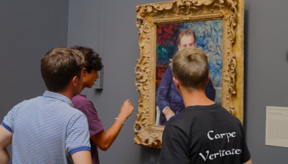 Three students admire a painting of Joe Guinee