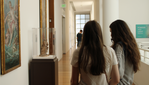 Two students admire a small sculpture in a glass case