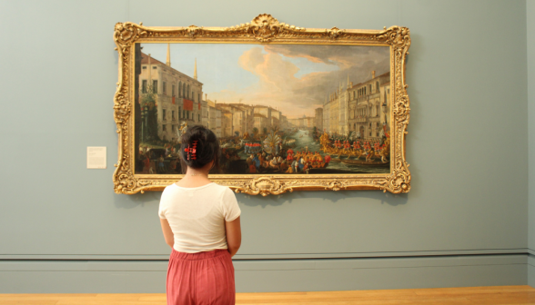 A student contemplates a painting of boating on a canal