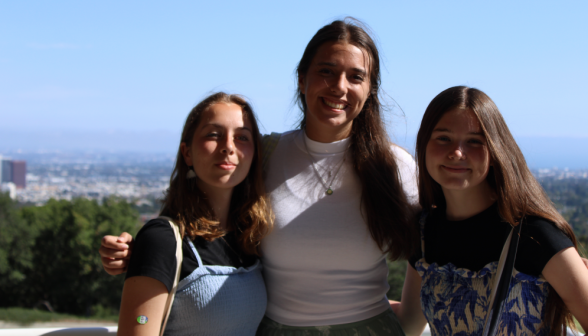 Three pose for a photo with the city in the background