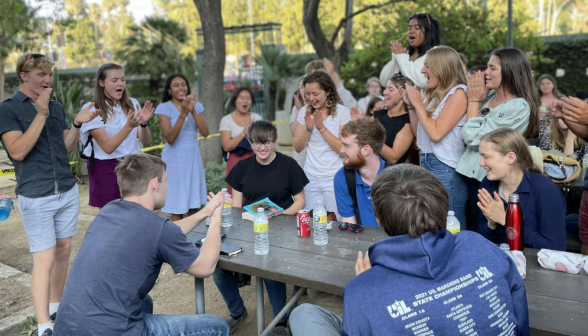 Students applaud around a picnic table