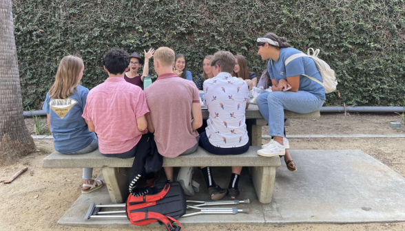 Students laugh and chat at one of the picnic tables