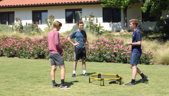 Three play Spikeball outside one of the dorms