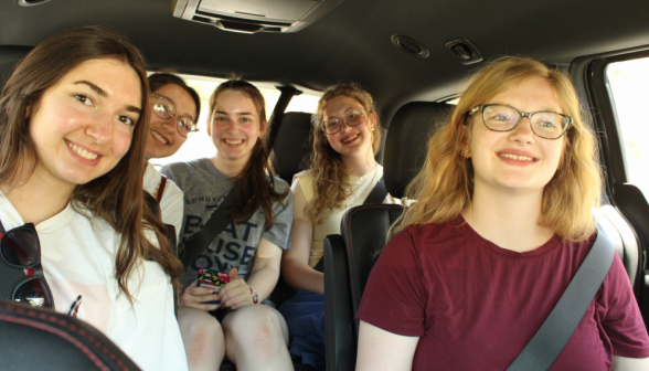 Five girls in a car smile for the camera