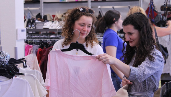 Two examine a shirt in a thrift store