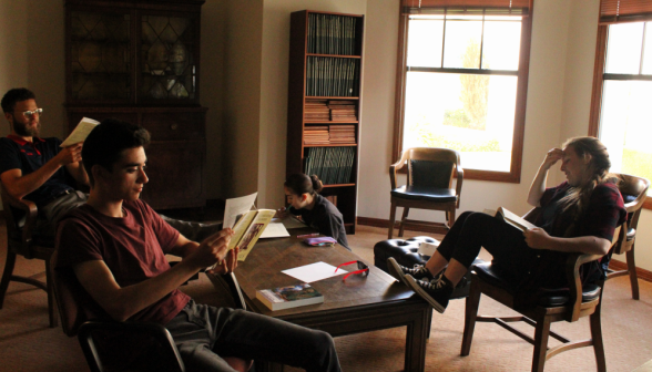 Three study around a table, while sunlight streams in through the windows