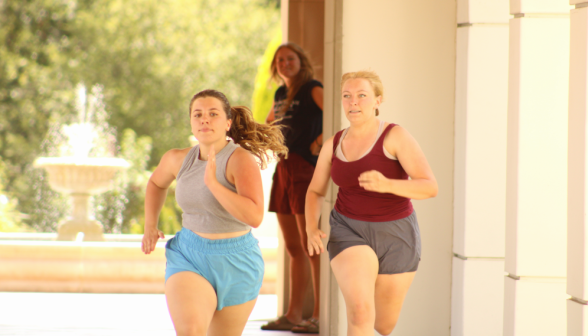 Two students sprint while a prefect looks on in the background