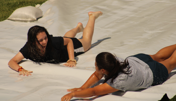 Two students laugh and chat on their way down the slide
