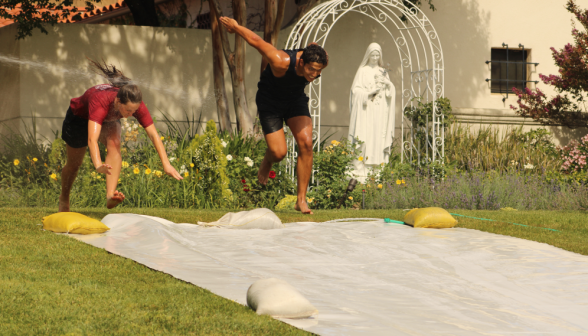 Two students mid-dive onto the slide