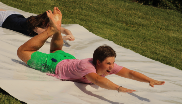 Yelling enthusiastically, a student goes down the slide