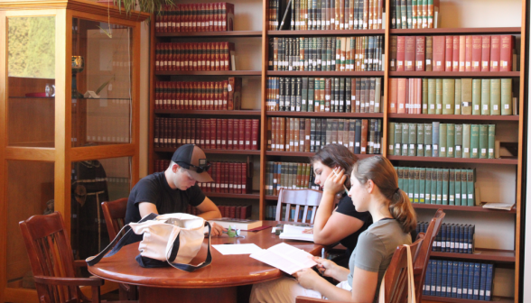 Three study beside a row of bookshelves