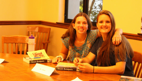 Two pose for a photo over their copy of Euclid