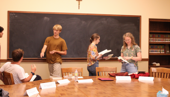 Four study their props at the blackboard